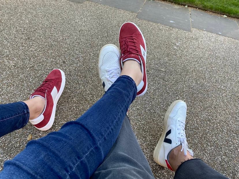 Two pairs of intertwined legs show two pairs of sneakers, including white sneakers from French brand Veja.