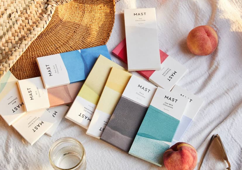 A white tablecloth spread with Mast chocolate bars in an array of varieties and fruit.