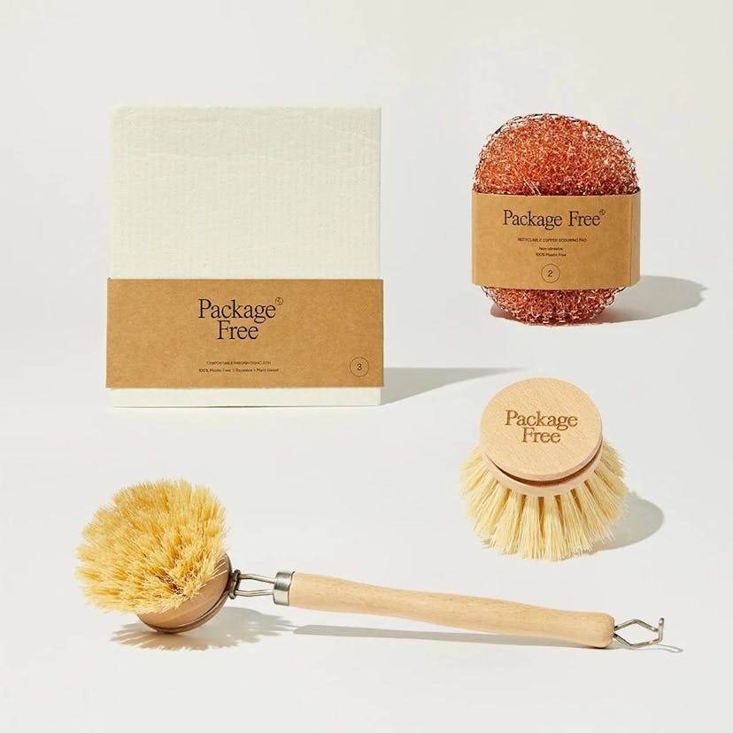 Package Free Shop's Kitchen Essentials Kit, including a copper scrubber, a wooden scrub brush with extra brush head, and a Swedish-style dishcloth.