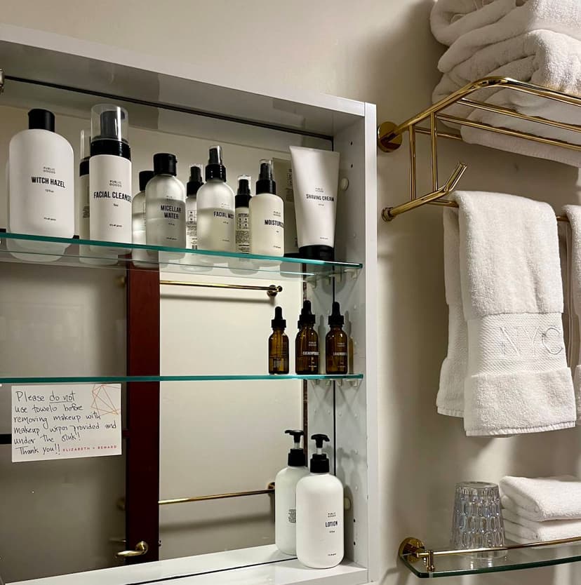 An open, mirrored bathroom cabinet with shelves stocked with toiletries from Public Goods.