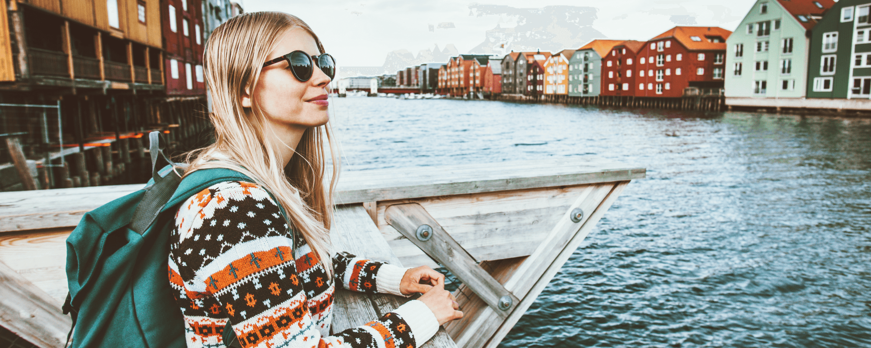 Woman wearing sunglasses and a backpack looking out over the water.