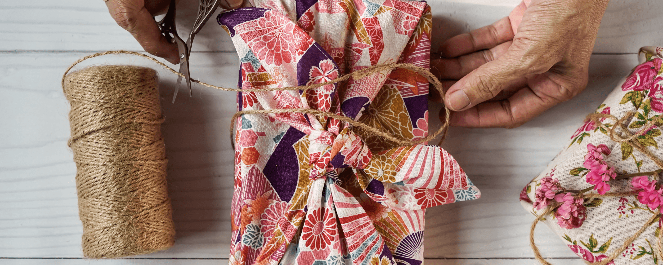 Hands wrapping a gift in sustainable materials.