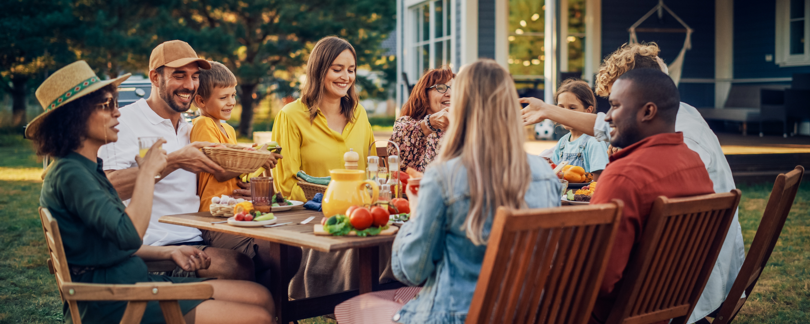 Group of smiling people dining at an outdoor table.