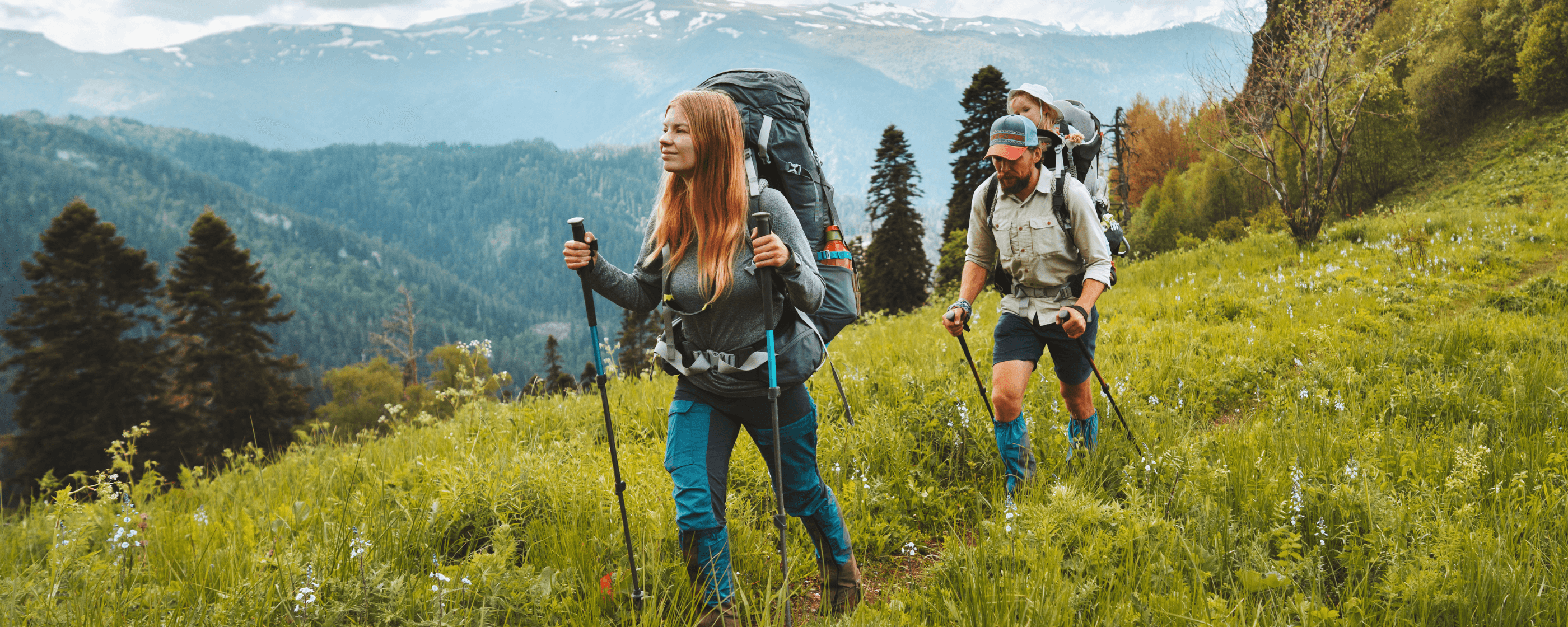 A family backpacking through a mountain landscape outdoors.