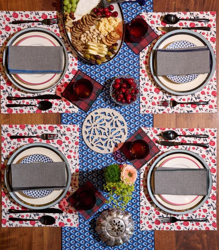 A table set with brightly colored blue, red, and white linens, with platters of fruits, nuts, and cheese.