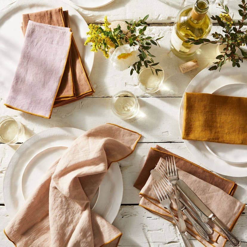 A white table set with plates and napkins in warm, muted tones