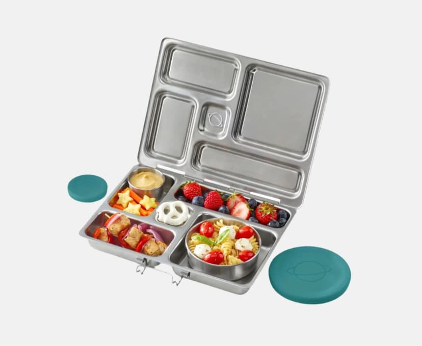 A bento-style stainless steel lunchbox filled with fruit, pretzels, and other food, made by Planet Box.